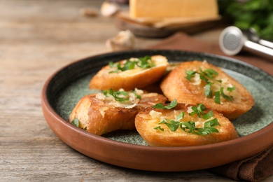 Slices of toasted bread with garlic, cheese and herbs on wooden table, closeup