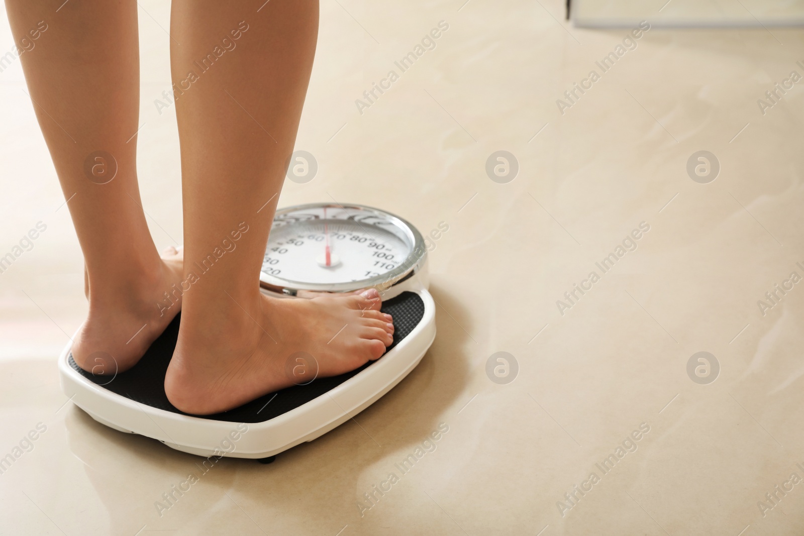 Photo of Woman standing on scales indoors, space for text. Overweight problem