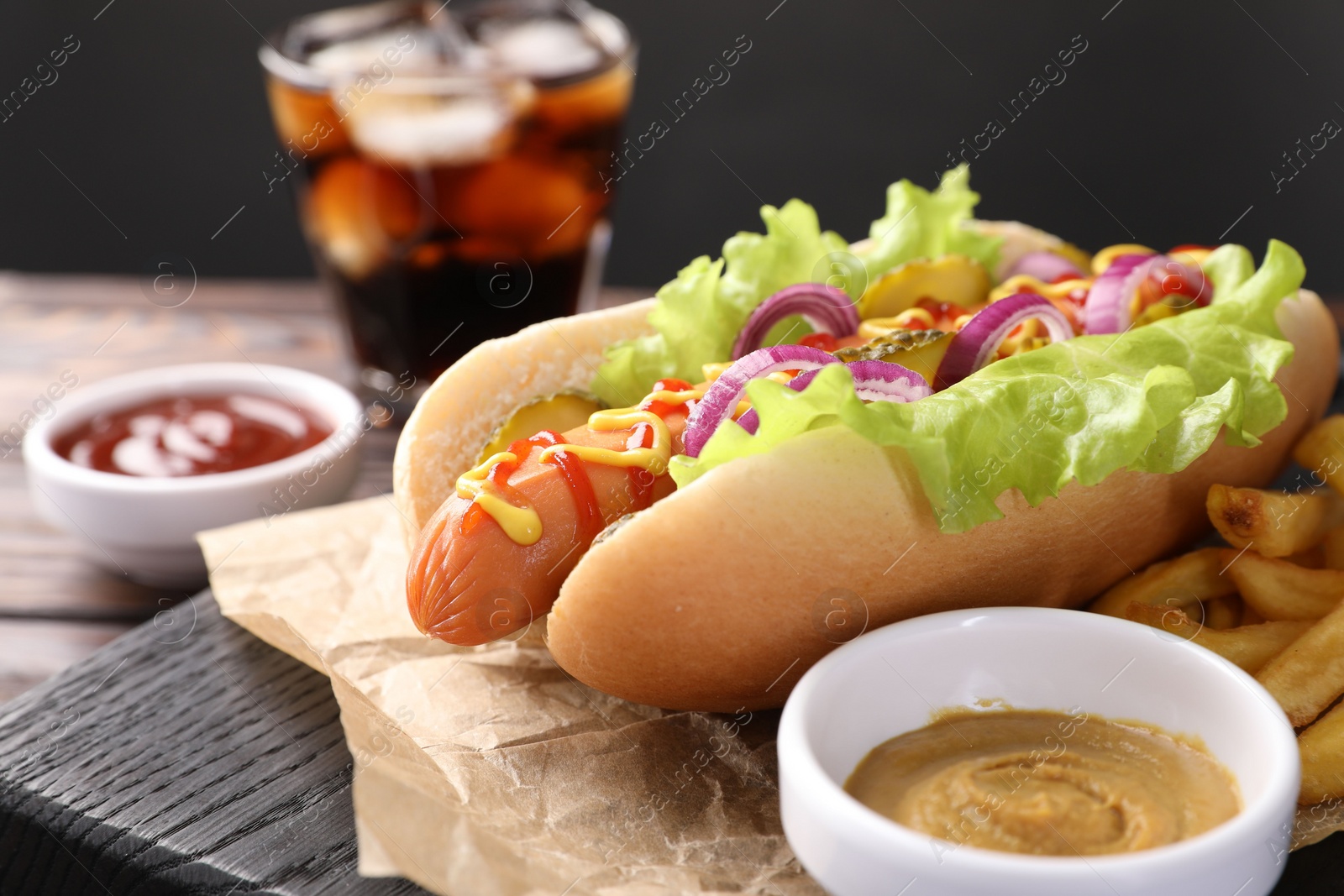 Photo of Delicious hot dog with lettuce, onion and pickle served on table, closeup