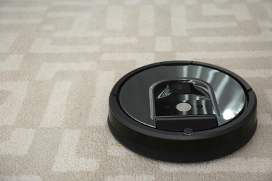 Modern robotic vacuum cleaner on carpet. Space for text