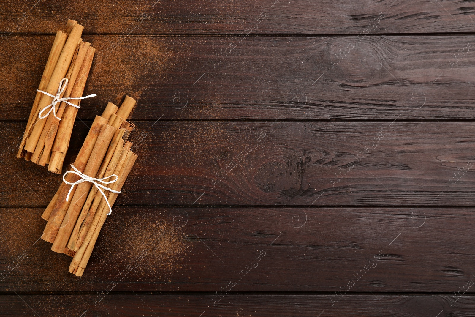 Photo of Aromatic cinnamon sticks and powder on wooden table, flat lay. Space for text