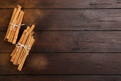 Aromatic cinnamon sticks and powder on wooden table, flat lay. Space for text