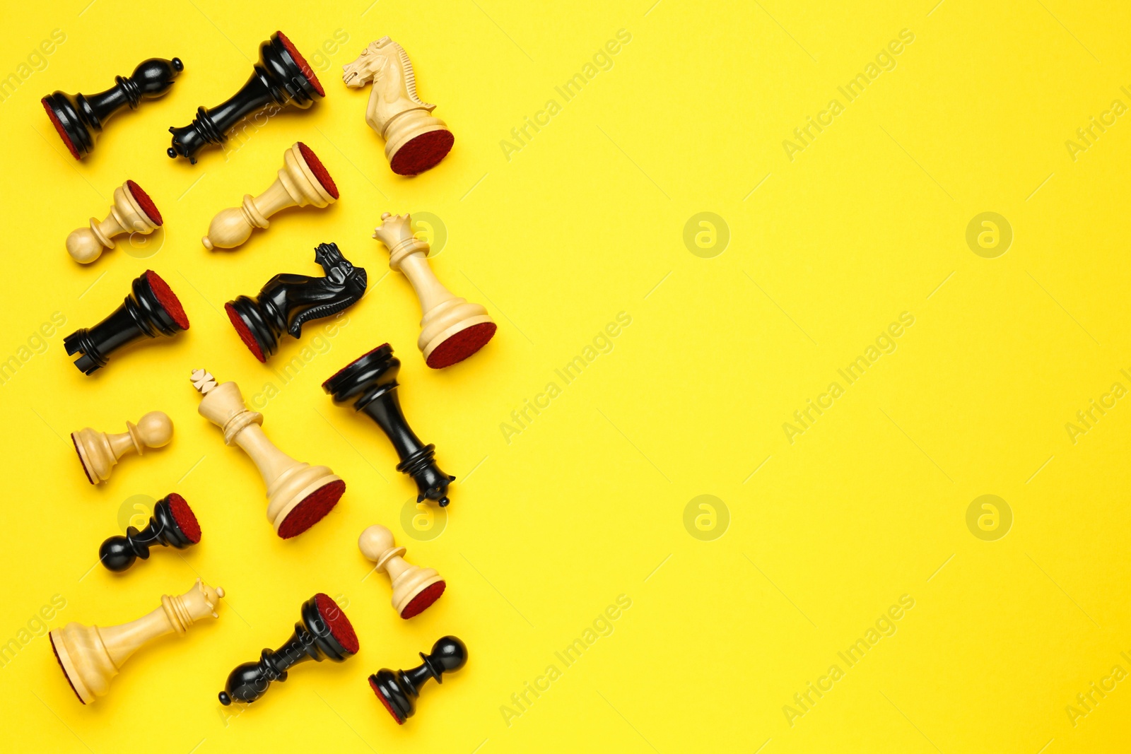 Photo of Many different chess pieces on yellow background, flat lay. Space for text