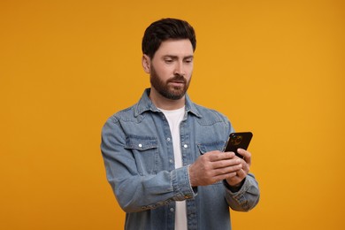 Photo of Handsome man with smartphone on orange background