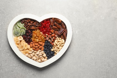 Photo of Heart shaped plate with different dried fruits and nuts on table. Space for text