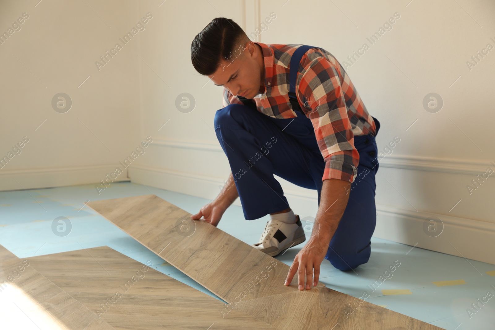 Photo of Professional worker installing new parquet flooring indoors