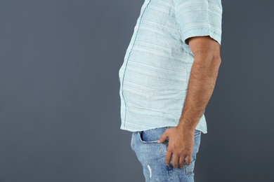 Overweight man on gray background, closeup view with space for text