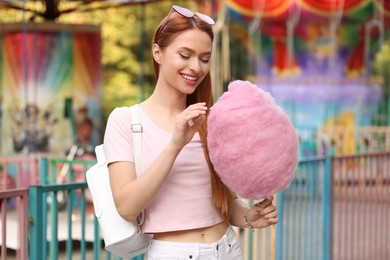 Smiling woman with cotton candy at funfair