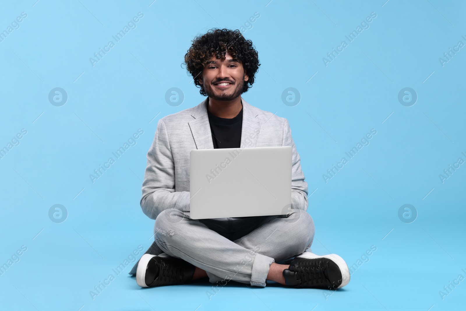 Photo of Smiling man with laptop on light blue background, space for text