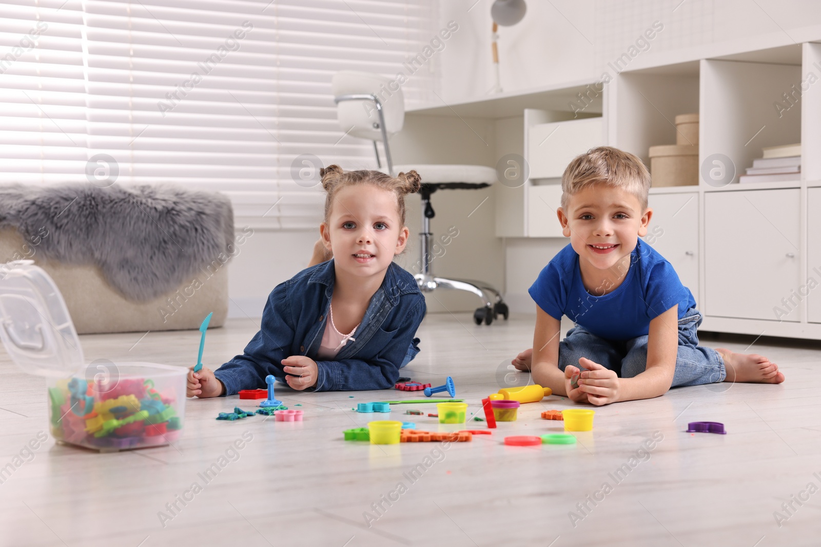 Photo of Cute little children playing on warm floor at home. Heating system