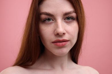 Portrait of beautiful woman with freckles on pink background, closeup