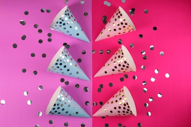 Photo of Bright party hats with confetti on color background, flat lay. Handmade decorations