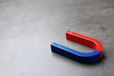 Photo of Red and blue horseshoe magnet on grey background. Space for text