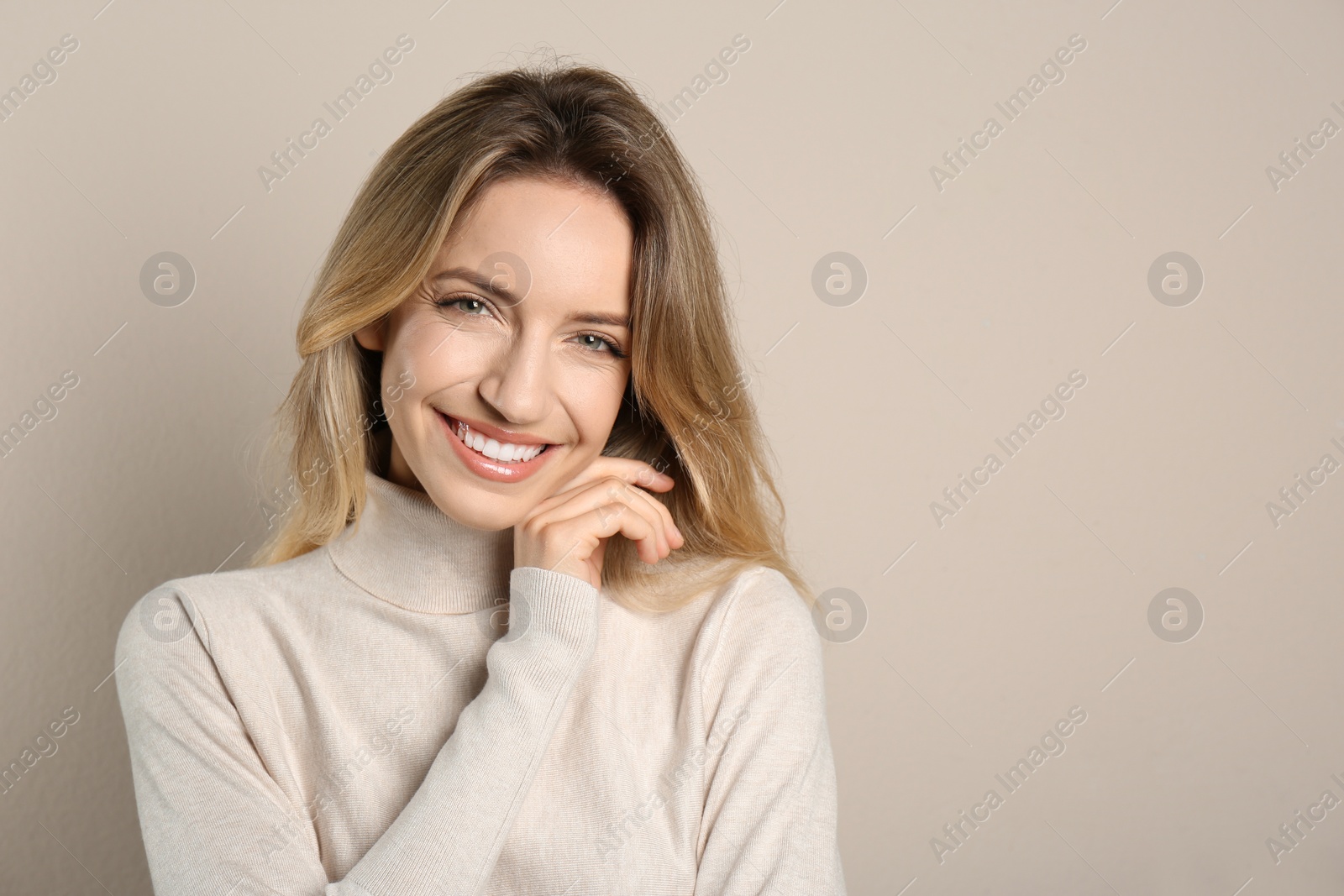 Photo of Portrait of happy young woman with beautiful blonde hair and charming smile on beige background. Space for text