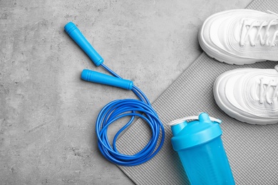 Photo of Flat lay composition with jump rope, gym equipment and space for text on grey background