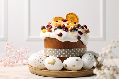 Traditional Easter cake with dried fruits and decorated eggs on white wooden table indoors
