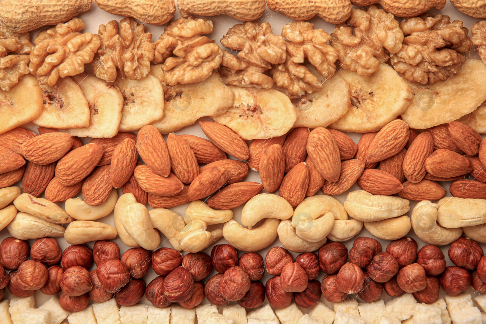 Photo of Different tasty nuts and dried fruits on beige background, flat lay