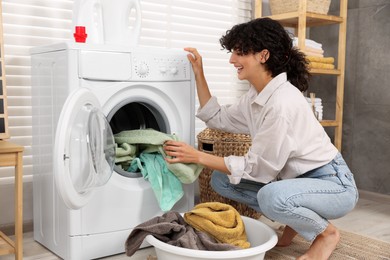 Woman taking laundry out of washing machine indoors