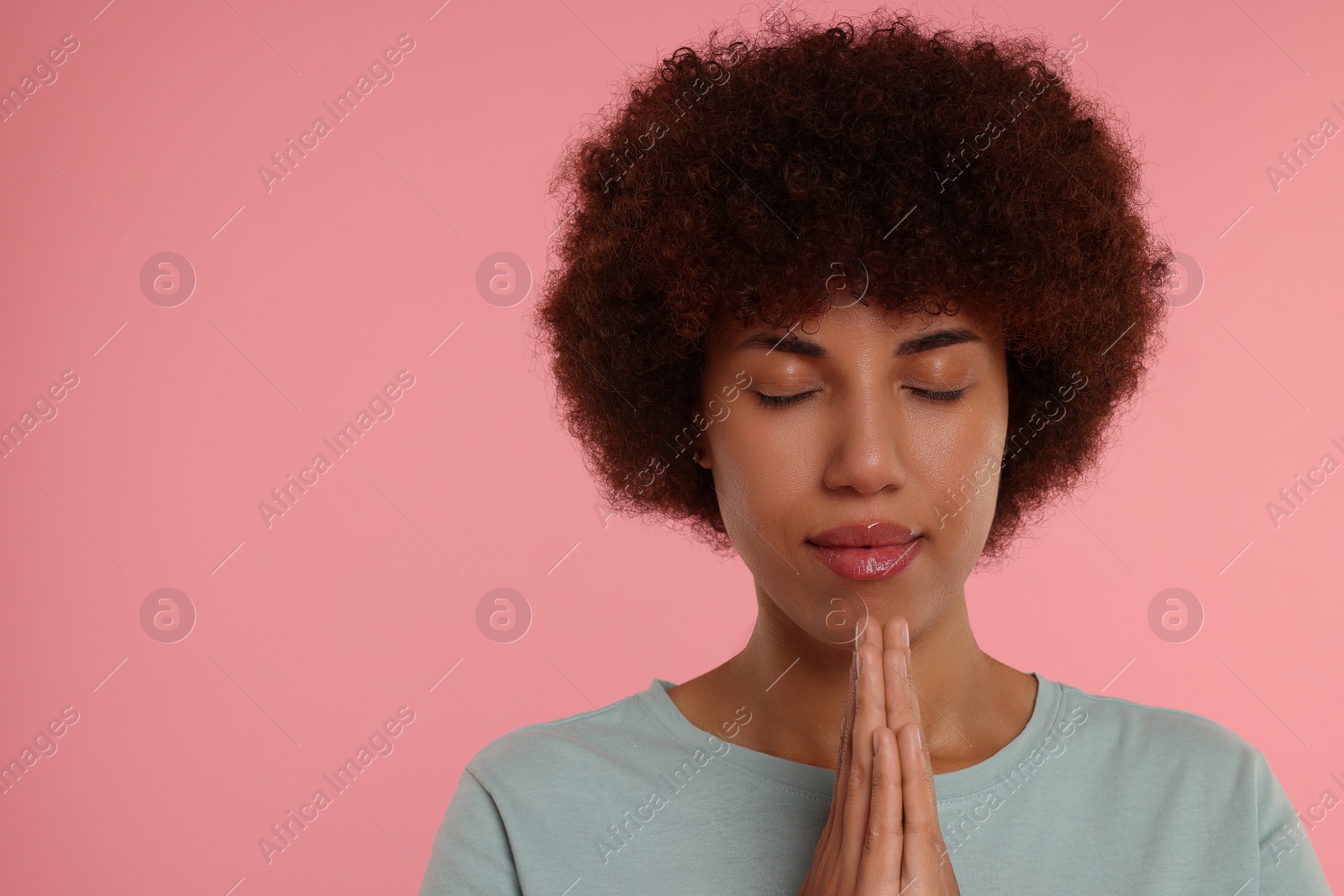 Photo of Woman with clasped hands praying to God on pink background. Space for text
