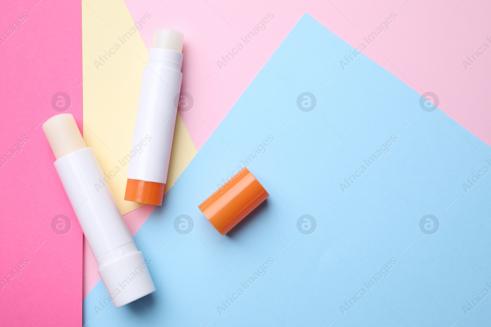 Photo of Hygienic lipsticks on color background, flat lay. Space for text
