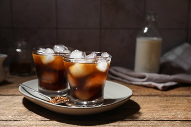 Refreshing iced coffee in glasses, ingredients and spoon on wooden table