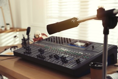 Photo of Microphone near professional mixing console in radio studio