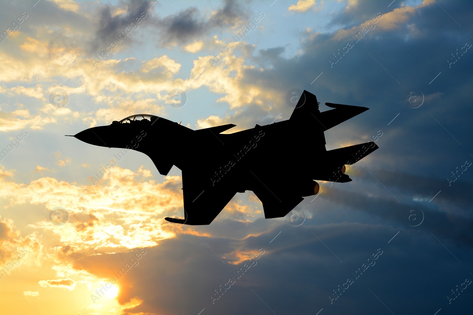 Image of Silhouette of jet fighter in cloudy sky at sunrise