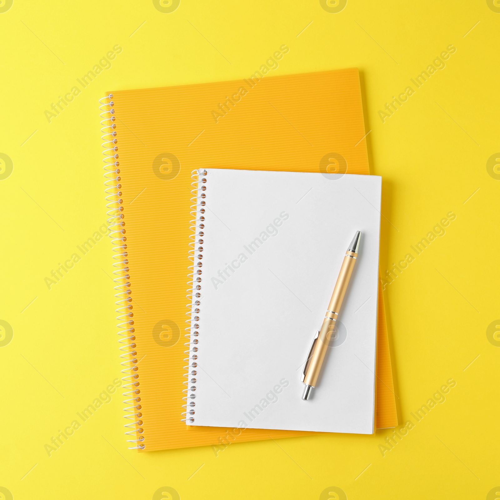 Image of Notebooks and pen on yellow background, top view
