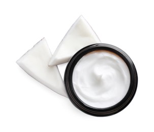 Jar of hand cream and coconut pieces on white background, top view