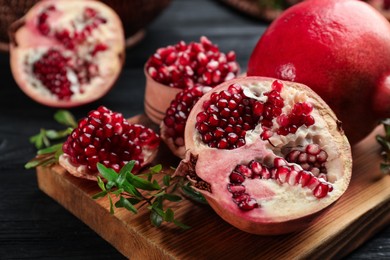 Delicious ripe pomegranates on black wooden table, closeup