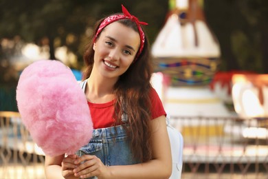 Photo of Stylish young woman with cotton candy at funfair