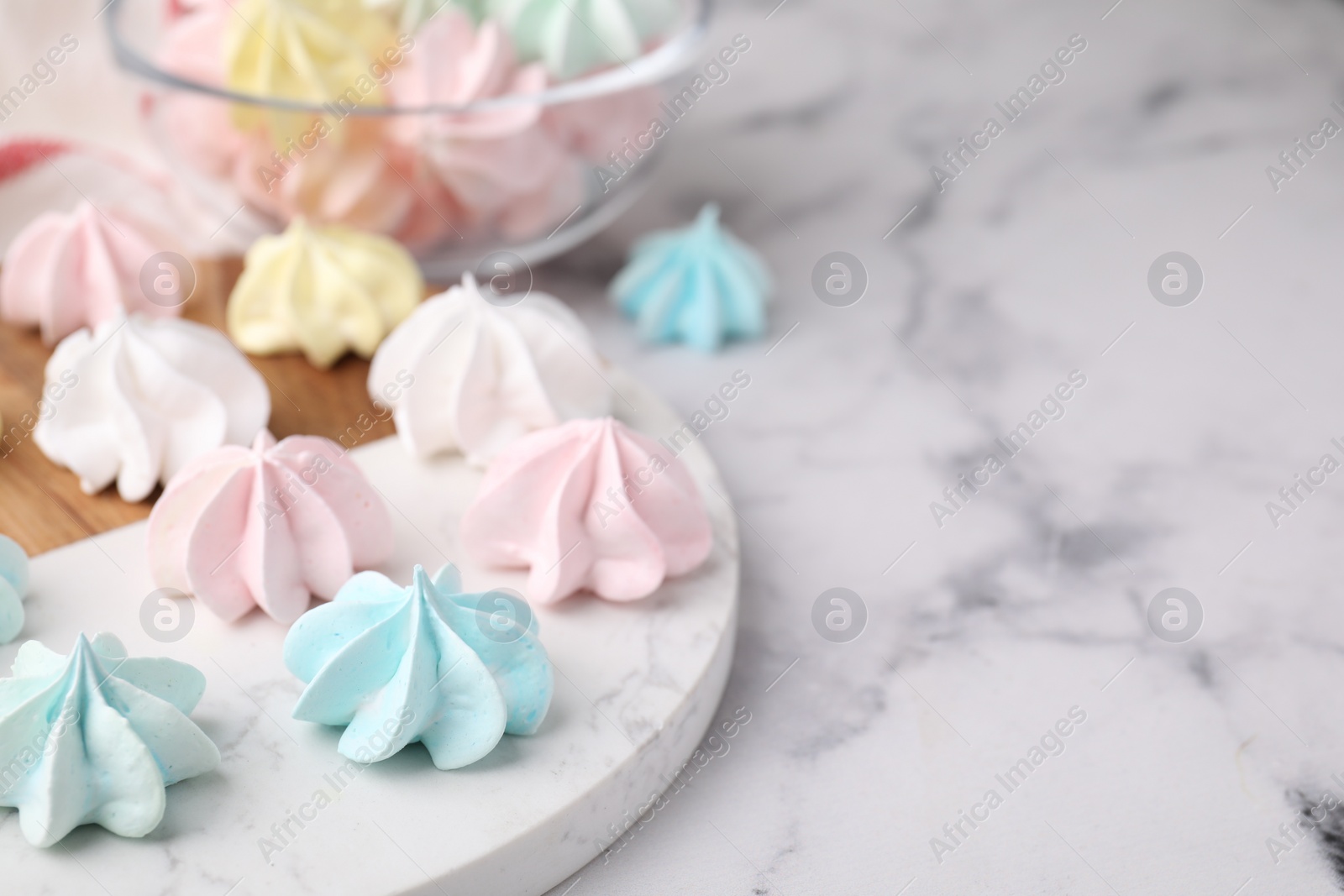 Photo of Tray with tasty meringue cookies on white marble table, closeup. Space for text