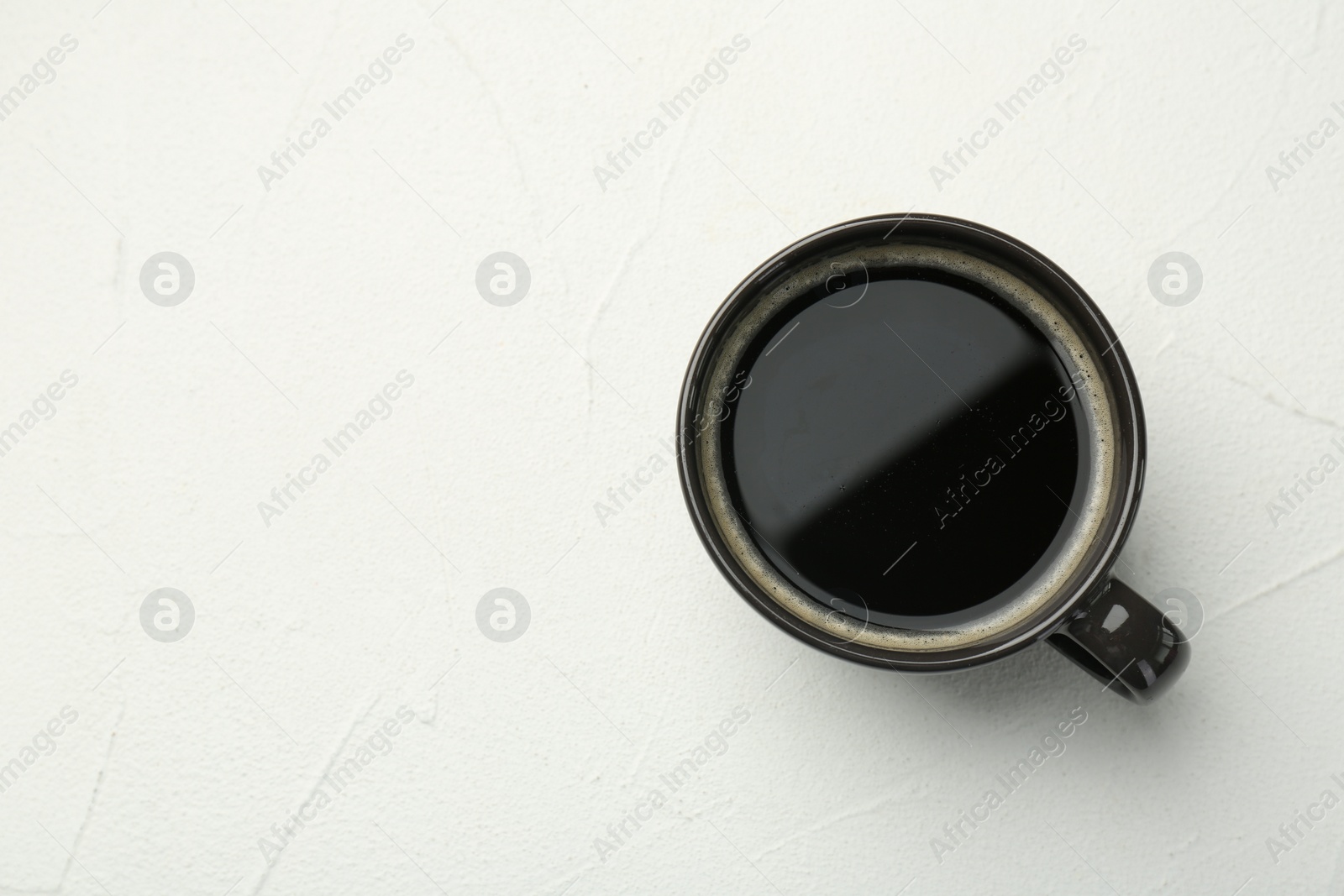 Photo of Hot coffee in cup on white textured table, top view. Space for text