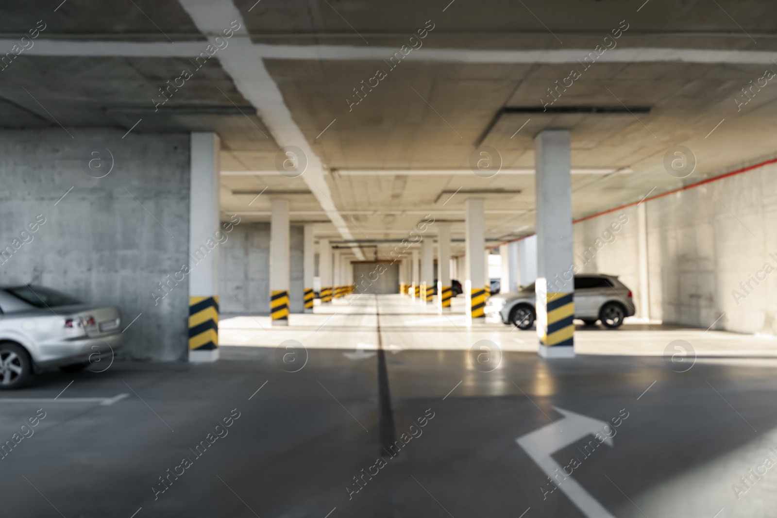 Photo of Blurred view of open parking garage with cars on sunny day
