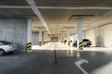 Blurred view of open parking garage with cars on sunny day