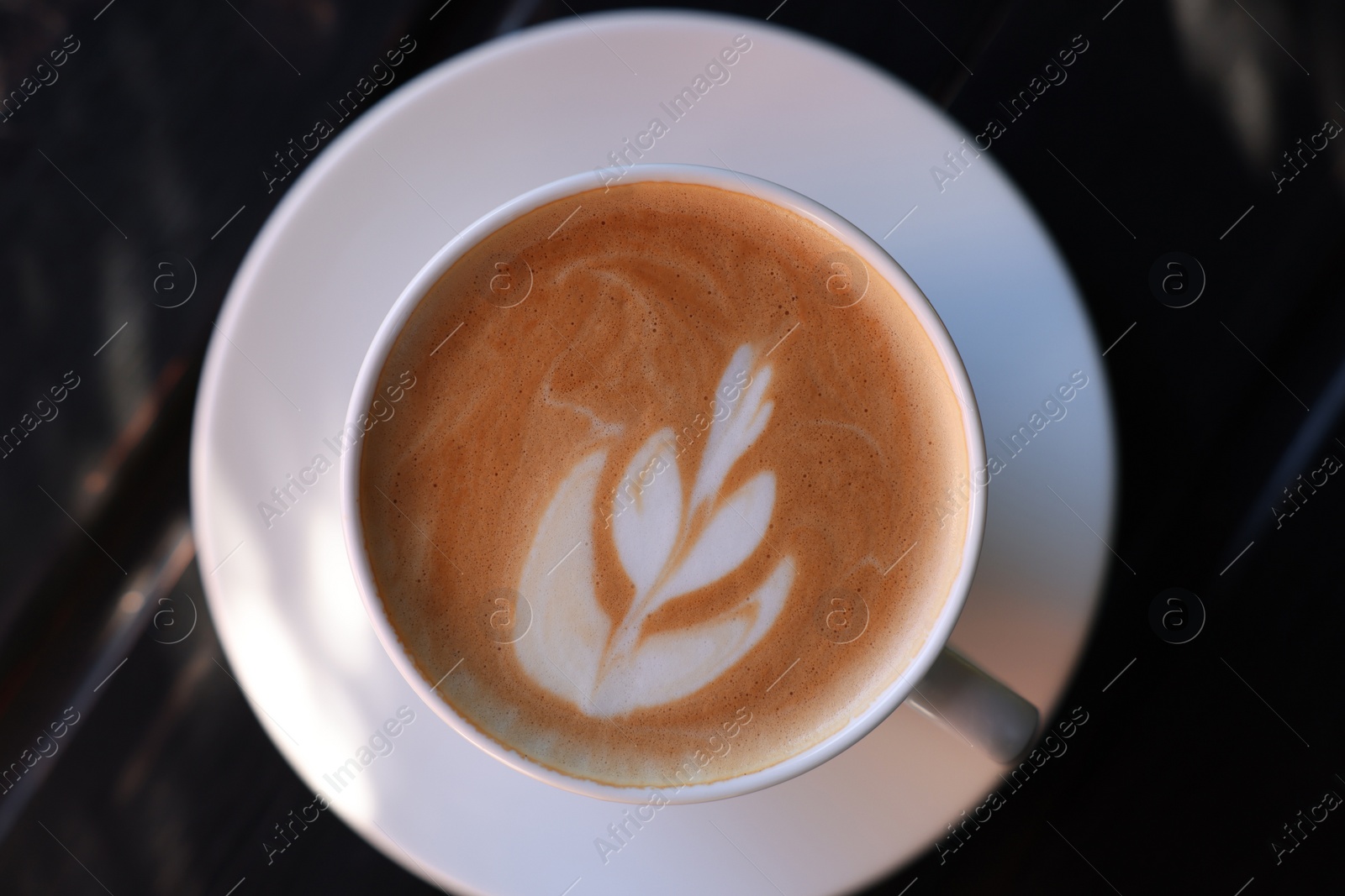 Photo of Cup of aromatic coffee with foam on wooden table, top view