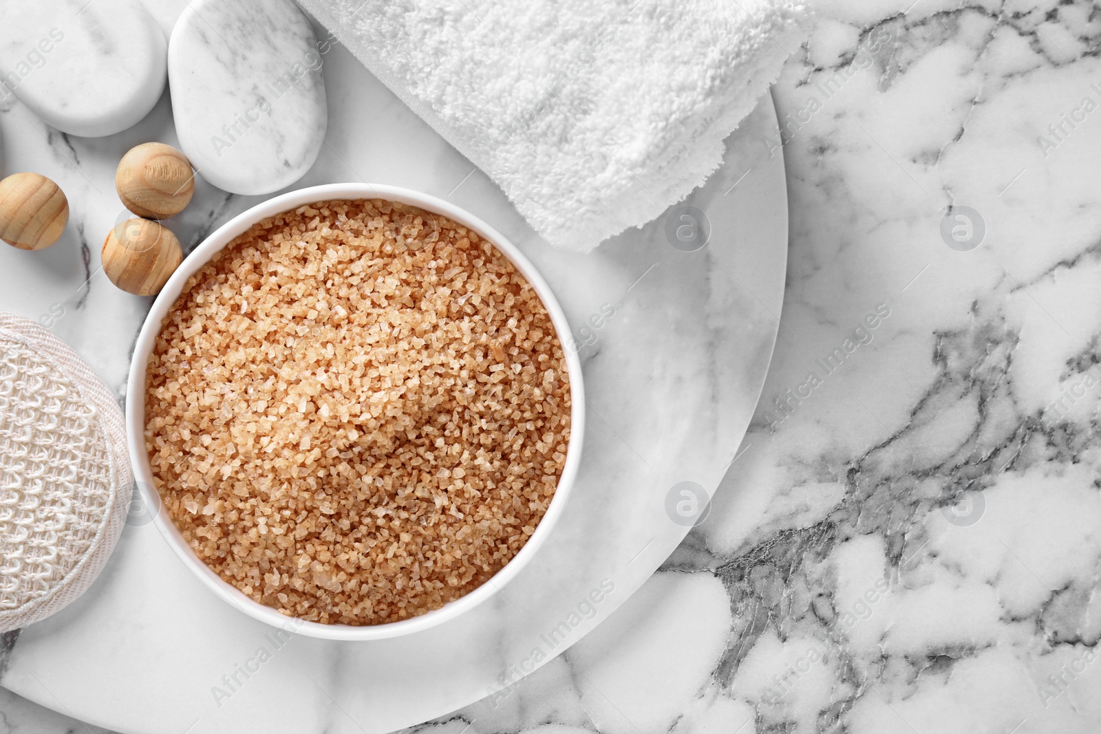 Photo of Flat lay composition with brown sea salt on marble background, space for text. Spa treatment