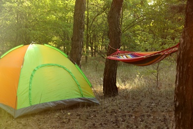 Photo of Colorful tent and empty comfortable hammock in forest