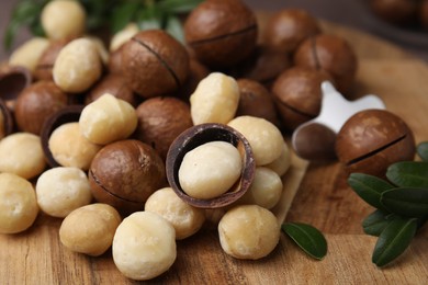 Photo of Tasty organic Macadamia nuts on wooden board, closeup