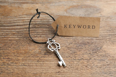 Photo of Vintage key and tag wIth word KEYWORD on wooden table