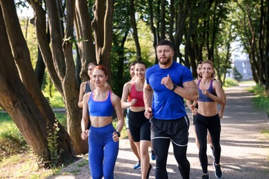 Group of people running in park on sunny day