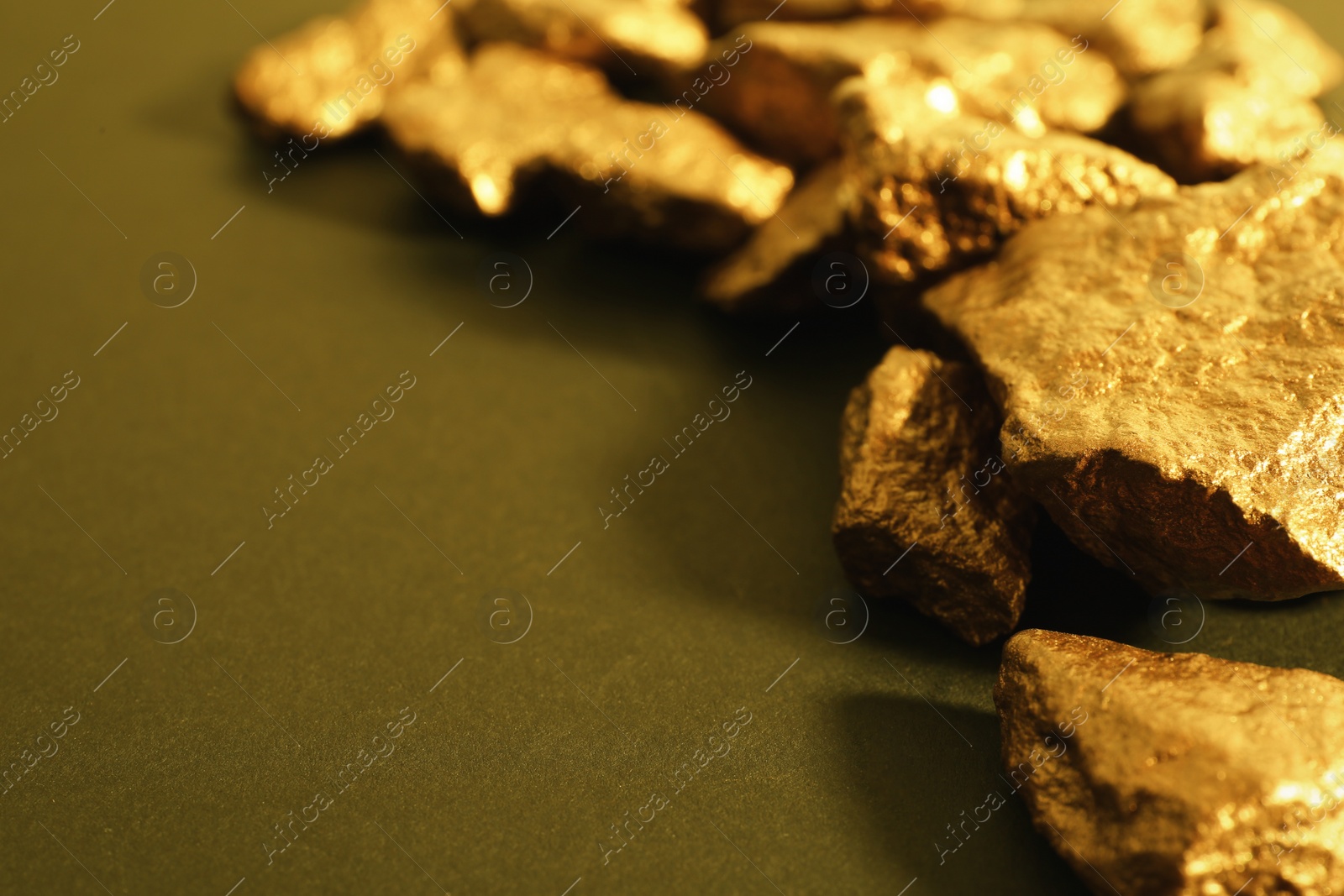 Photo of Pile of gold nuggets on color background. Space for text