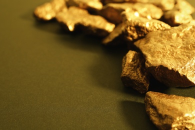 Photo of Pile of gold nuggets on color background. Space for text