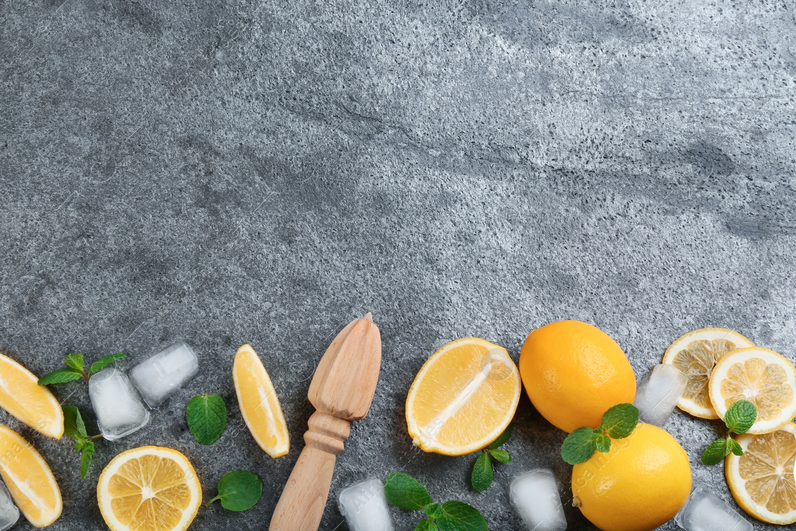 Photo of Lemonade layout with juicy lemon slices, mint and ice cubes on grey table, top view. Space for text