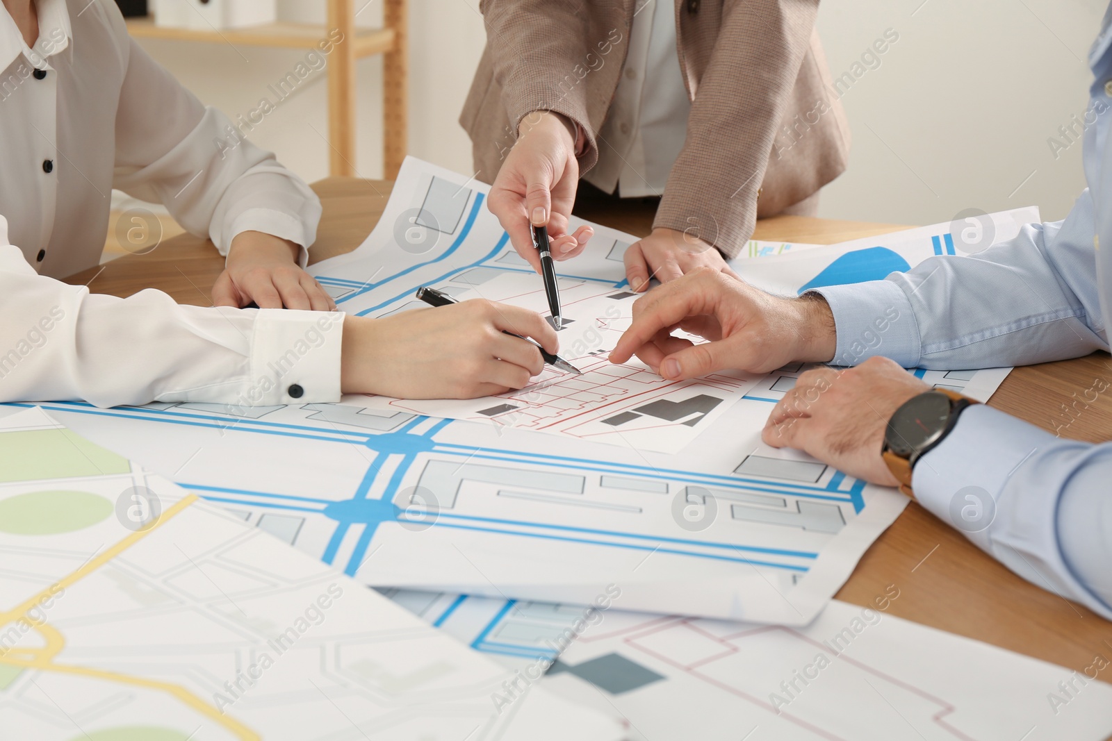 Photo of Professional cartographers working with cadastral map at table in office, closeup