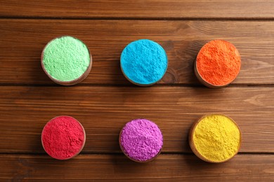 Colorful powder dyes on wooden background, flat lay. Holi festival