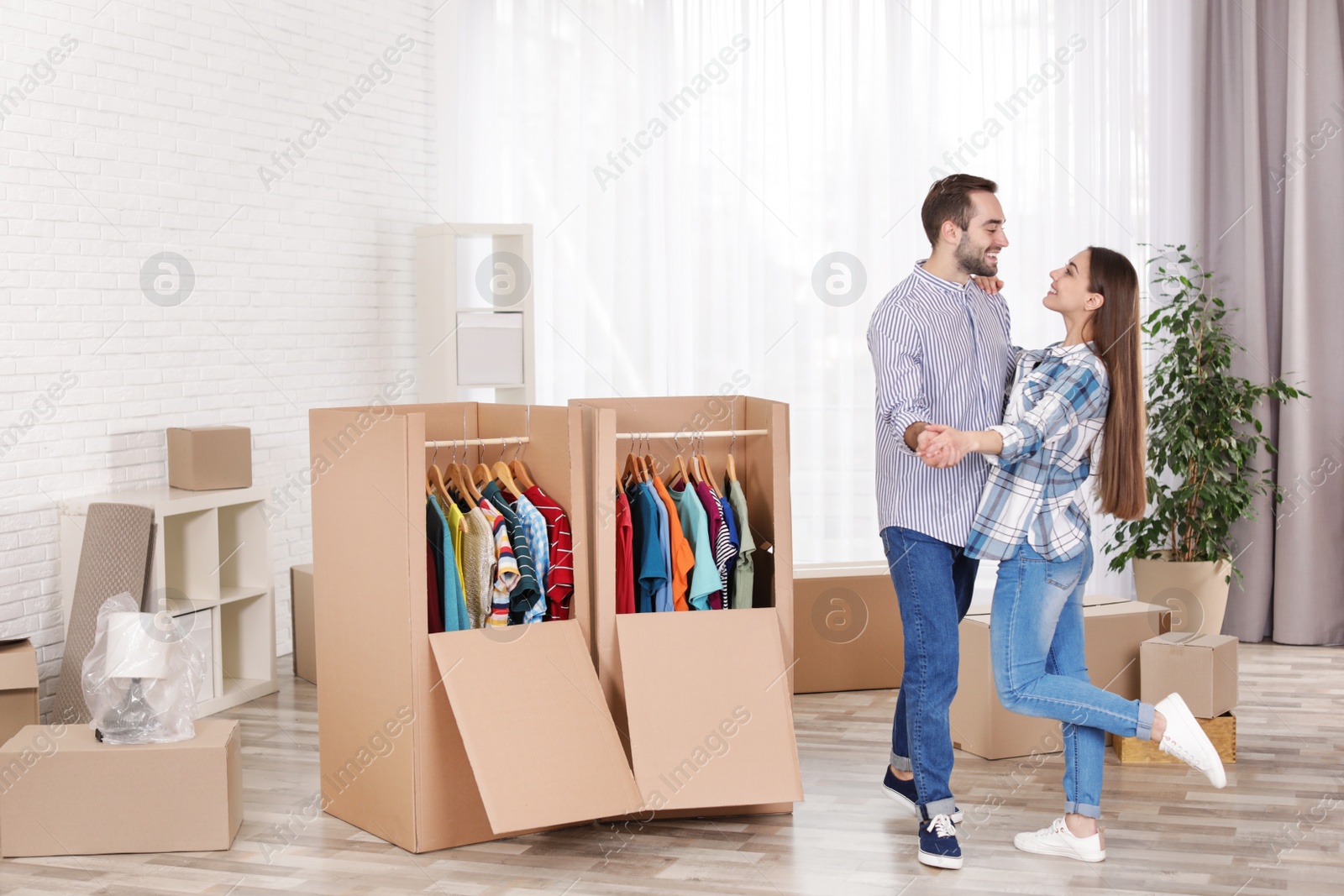Photo of Young couple dancing near wardrobe boxes at home