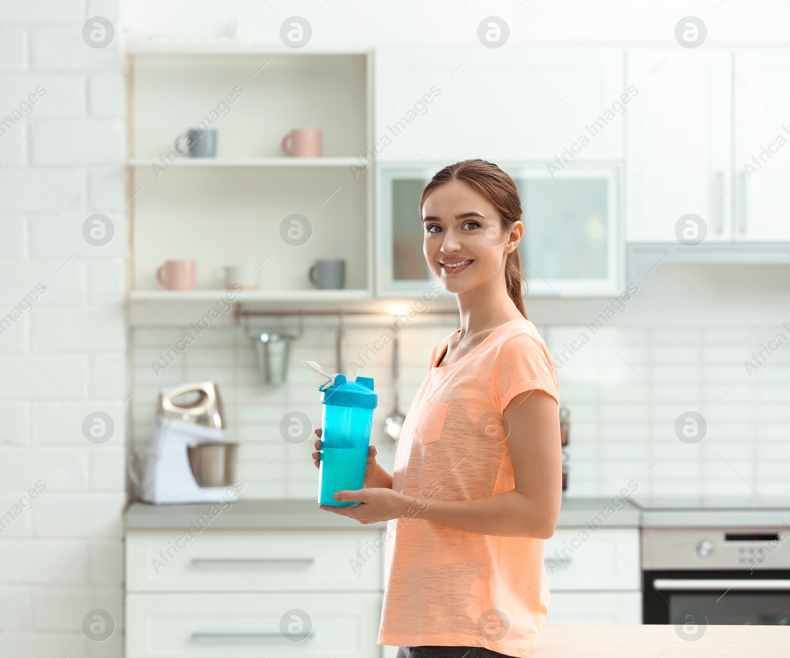 Photo of Athletic young woman with protein shake in kitchen