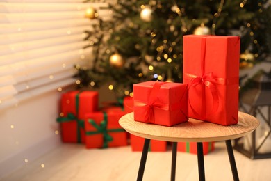 Photo of Beautifully wrapped Christmas gifts on wooden table in living room, space for text