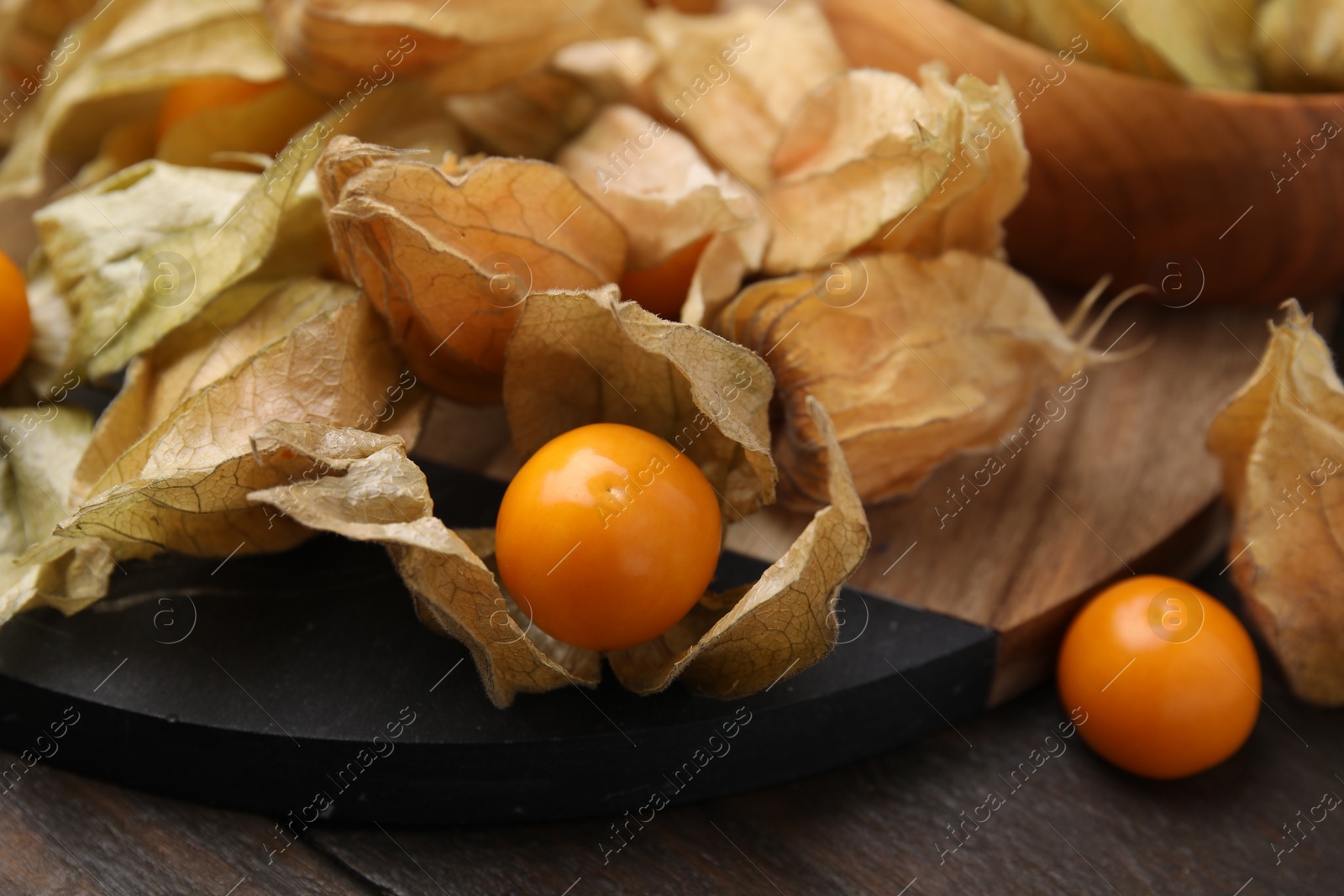 Photo of Ripe physalis fruits with calyxes on wooden table, closeup